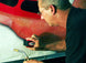 Person using a torch to work on a red vehicle panel