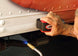 Person using a tool on the undercarriage of an airplane