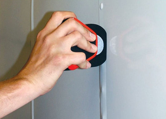 Hand using a red tool to open a cabinet door