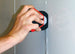 Hand using a red tool to open a cabinet door
