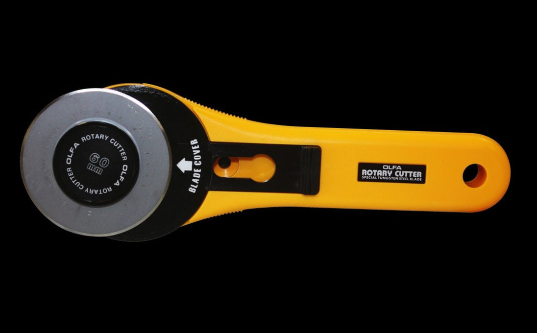 Rotary cutter with yellow handle and black blade on a black background