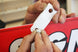 Person attaching a white plastic clip to a red and black sign.