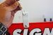 Hand attaching a metal clip to a red sign with 'SIGN' printed on it.