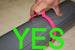 Hand holding a pink object with the word 'YES' in green text overlay on a neutral background