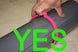 Hand holding a pink object with the word 'YES' in green text overlay on a neutral background