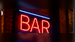 Illustrative red and blue illuminated BAR neon sign in an indoor setting; application illustration for Allanson SS935ICH indoor neon power supply