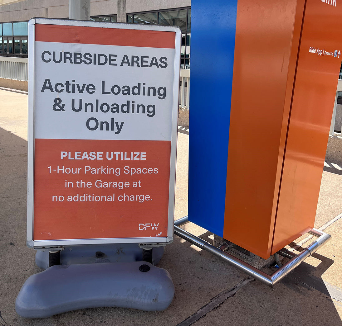 Sign indicating curbside active loading and unloading areas with a blue and orange structure in the background.