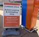 Sign indicating curbside active loading and unloading areas with a blue and orange structure in the background.