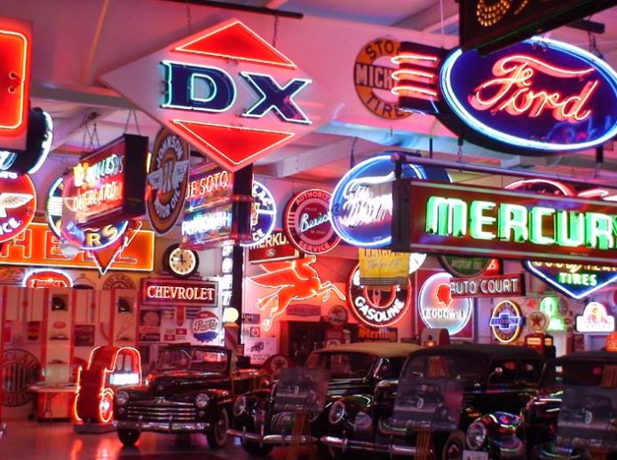 Neon signs and vintage cars in a showroom setting
