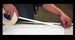 Person applying tape to a long strip of paper or fabric.