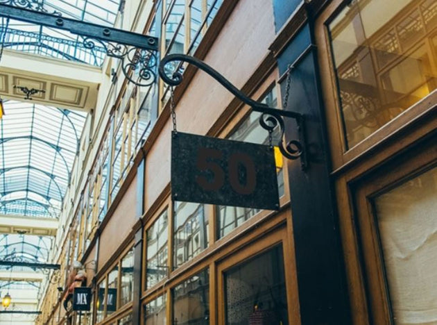 Decorative sign with number 50 hanging from an ornate metal bracket in a building interior.