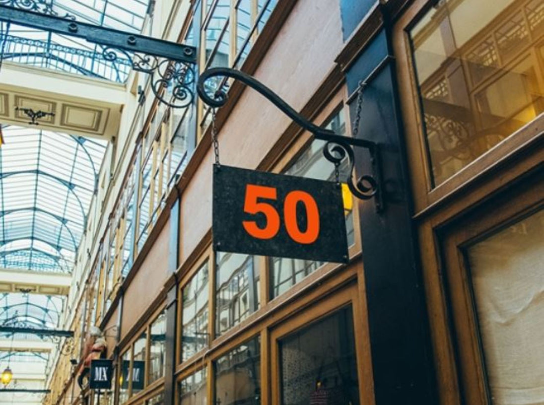 Sign with the number 50 hanging from a building in an indoor shopping arcade.