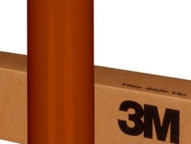 Cardboard box with 'This Side Up' and '3M' branding, partially obscured by a vertical brownze object.