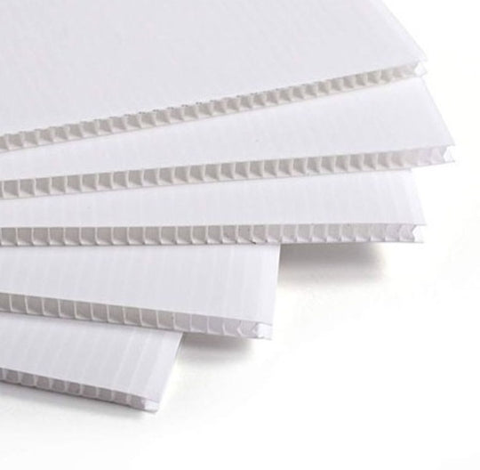 Stack of white corrugated plastic sheets on a white background