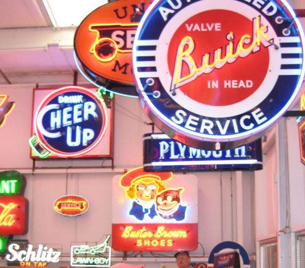 Collection of vintage neon signs including Buick, Cheer Up, and Schlitz.