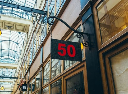 Sign with the number 50 hanging from a building in an indoor shopping arcade.