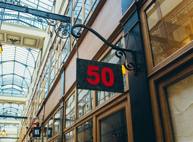 Sign with the number 50 hanging from a building in an indoor shopping arcade.