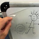 Hand holding a clear plastic sheet over a whiteboard with stick figure drawings of a girl and a sun.