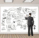 Man in a suit standing in front of a whiteboard with various diagrams and notes.