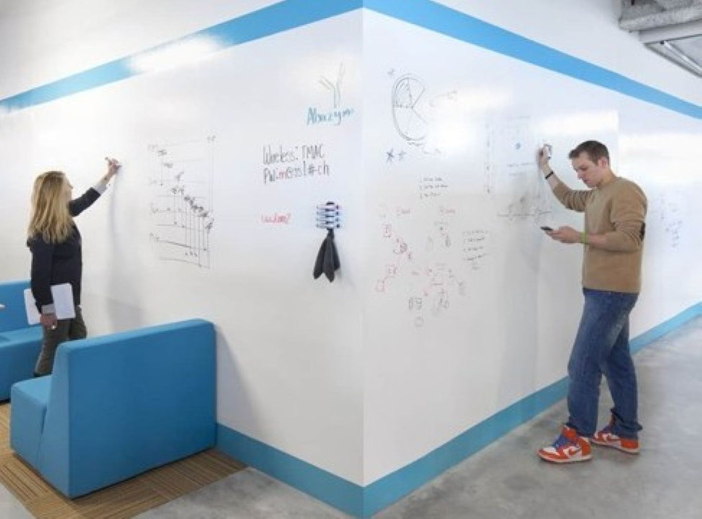 Two people interacting with a whiteboard in a modern office setting.