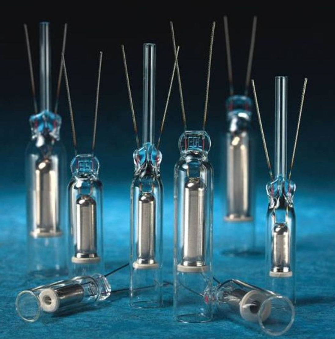Set of glass vials with metal components on a blue background