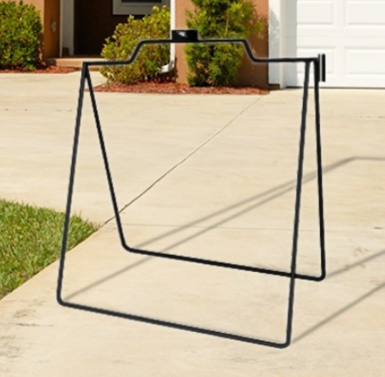 Black metal chair frame on a concrete patio with a house and garden in the background