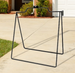 Black metal chair frame on a concrete patio with a house and garden in the background