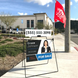Real estate sign with contact information and 'For Sale' label in front of a building.