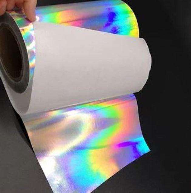 Roll of holographic foil with a hand holding it against a black background