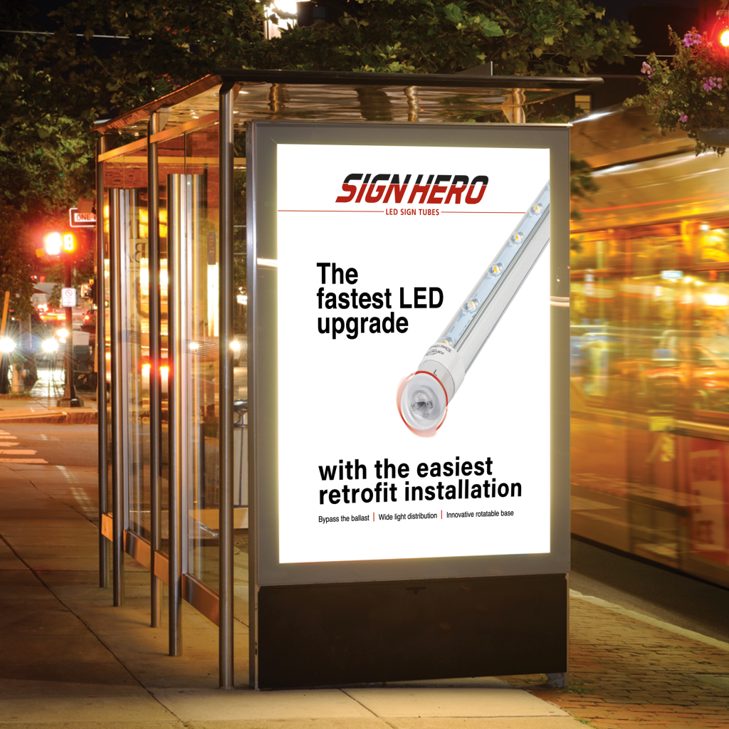 A tall outdoor LED sign display at a bus stop at night, showing a promotional ad for SIGN HERO LED Sign Lights with text and a graphic of a light fixture.