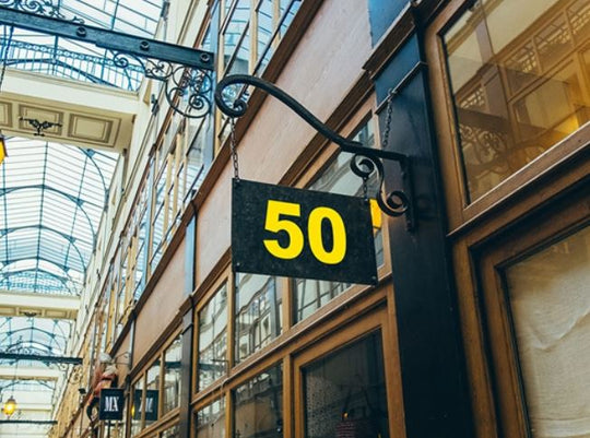 Sign with the number 50 hanging from a building in an indoor shopping arcade.