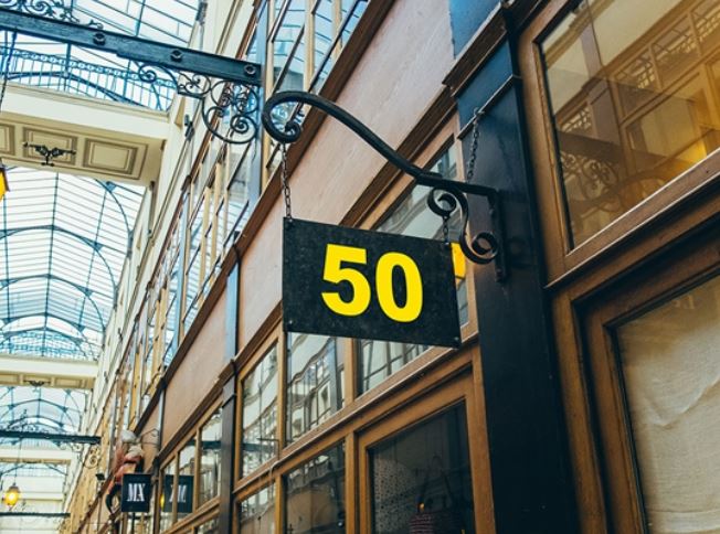 Sign with the number 50 hanging from a building in an indoor shopping arcade.