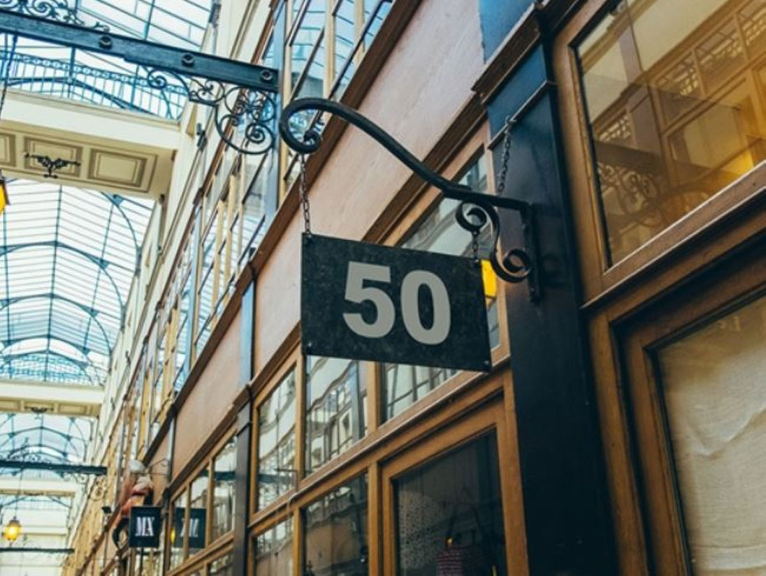 Building facade with a sign displaying the number 50 in an indoor setting with glass ceiling