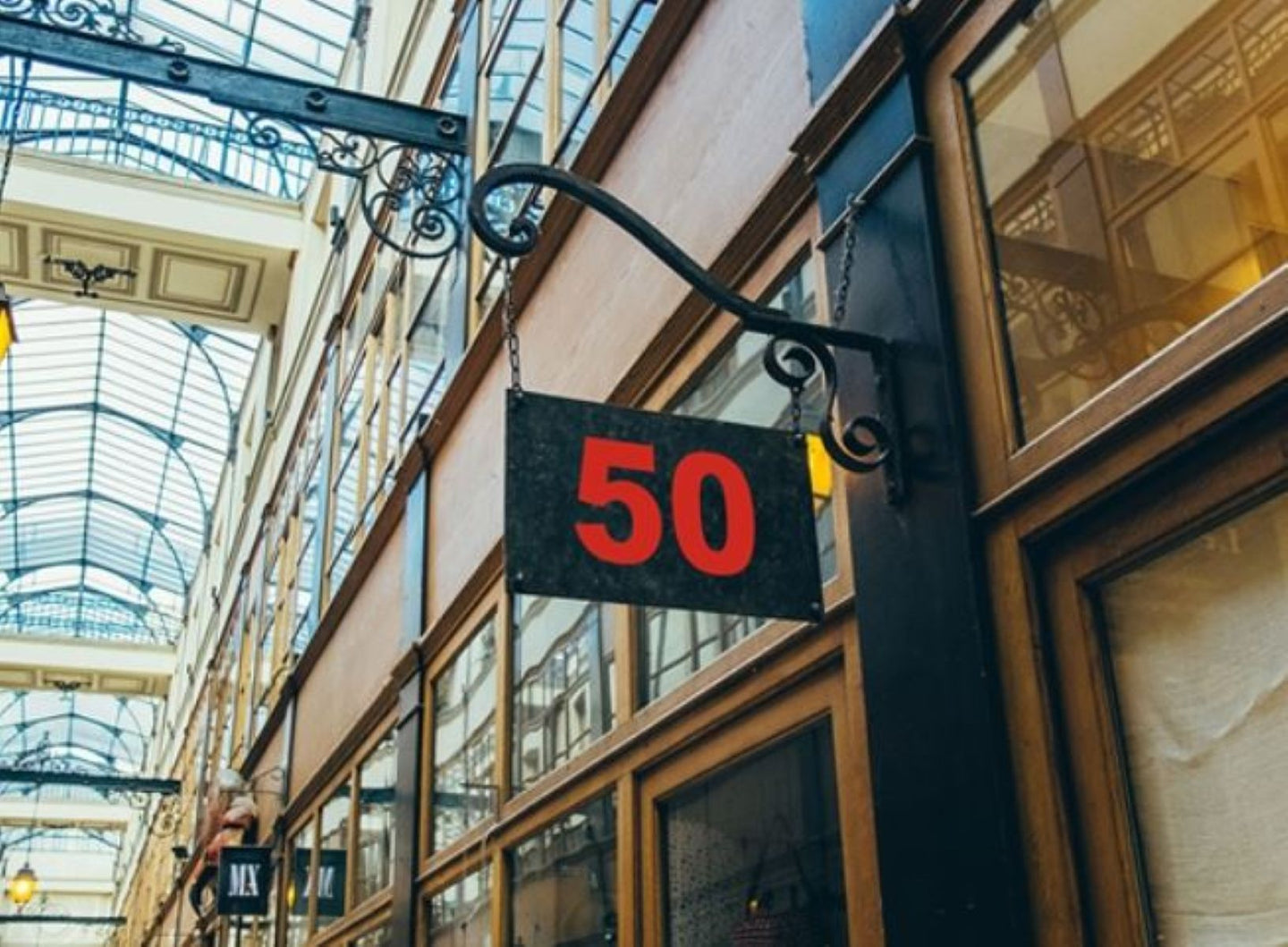 Sign with the number 50 hanging from an architectural structure in a shopping arcade.