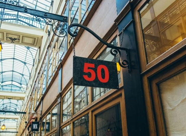 Sign with the number 50 hanging from an architectural structure in a shopping arcade.