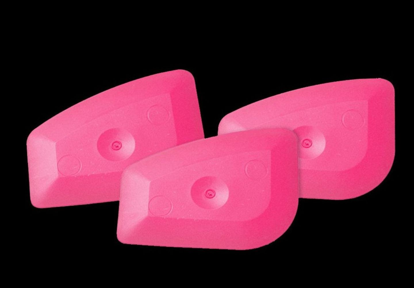 Three pink plastic wedges on a black background