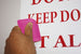 Hand holding a pink object against a white background with red text.