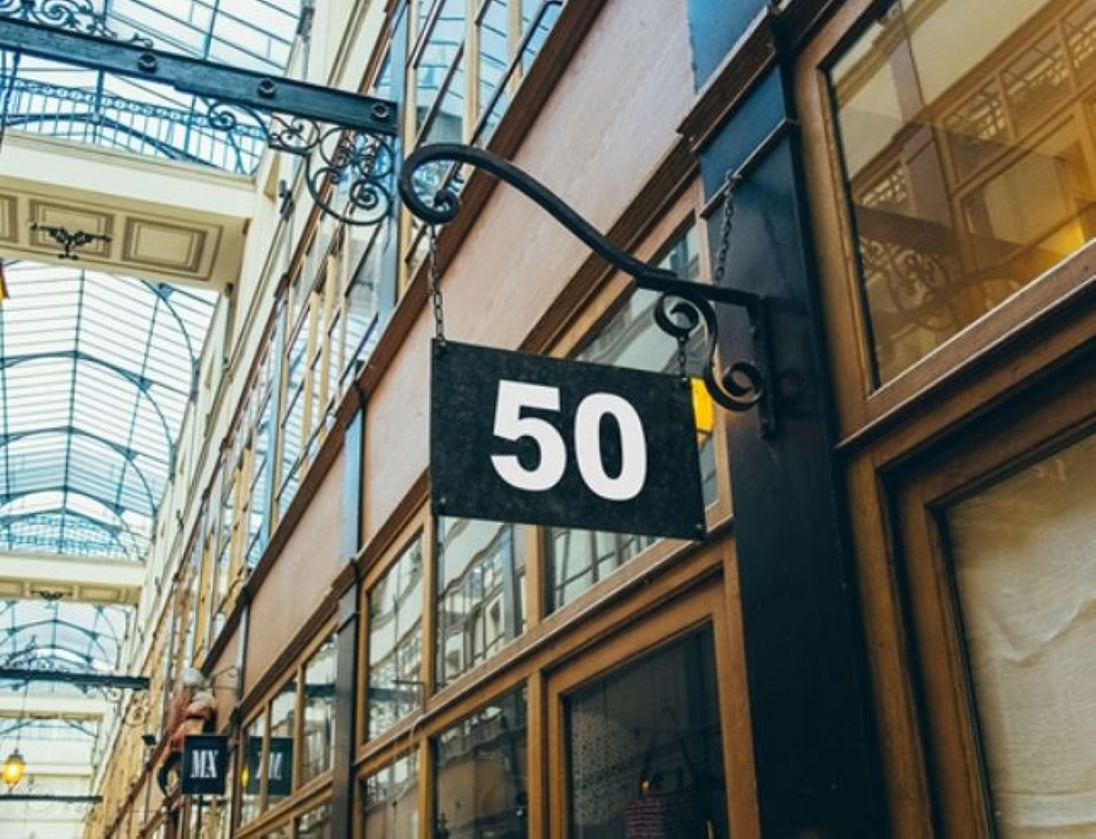 Building facade with a sign displaying the number 50 in an indoor setting with glass ceiling