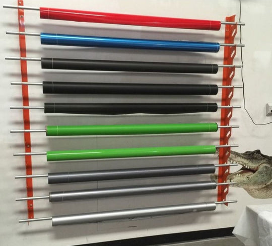 Set of colorful metal rods on a white wall with a crocodile model in the corner.