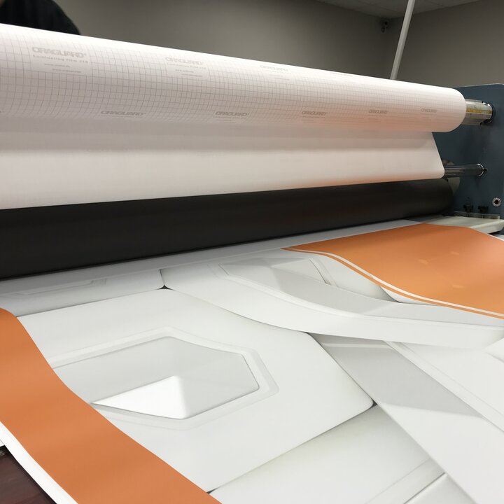 ORAGUARD 290 clear cast overlaminate being applied through a laminator