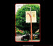 Giraffe-shaped street sign with a banner on a tree-lined street