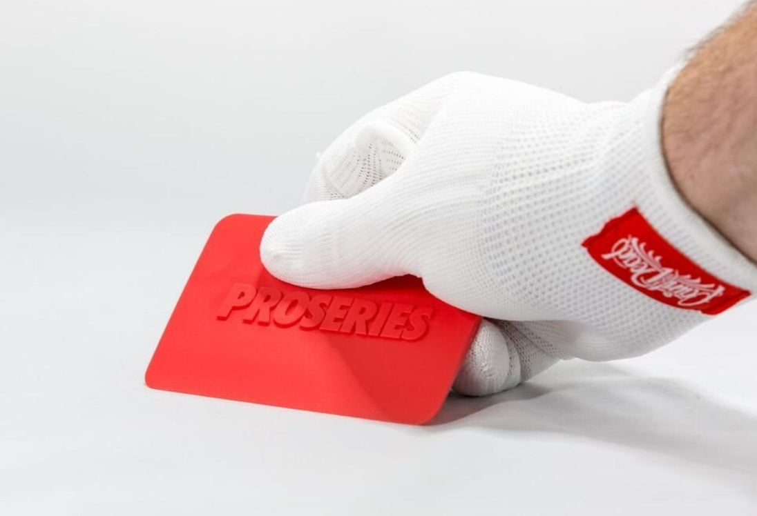Hand wearing a white glove holding a red tool labeled 'ProSeries' on a light gray background