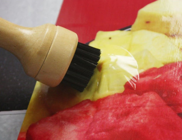 Wooden brush with black bristles on a red and yellow surface