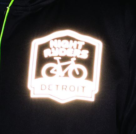 Reflective logo of 'Night Riders Detroit' on a dark background