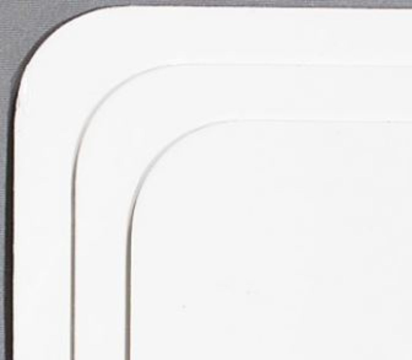 Close-up of a white plastic component with curved edges on a gray background