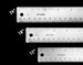 Three metal rulers with measurements in inches and millimeters on a black background