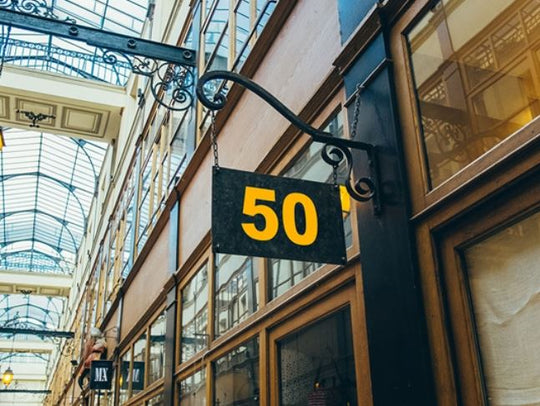 Number 50 sign hanging from a building in an indoor shopping arcade.