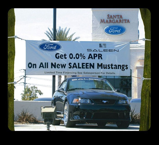 Ford dealership with a Saleen Mustang and promotional banner.