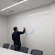 Person using a whiteboard in a conference room with chairs and lights.