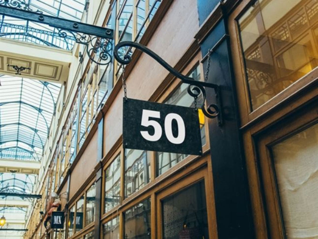 Building facade with a sign displaying the number 50 in an indoor setting with glass ceiling.